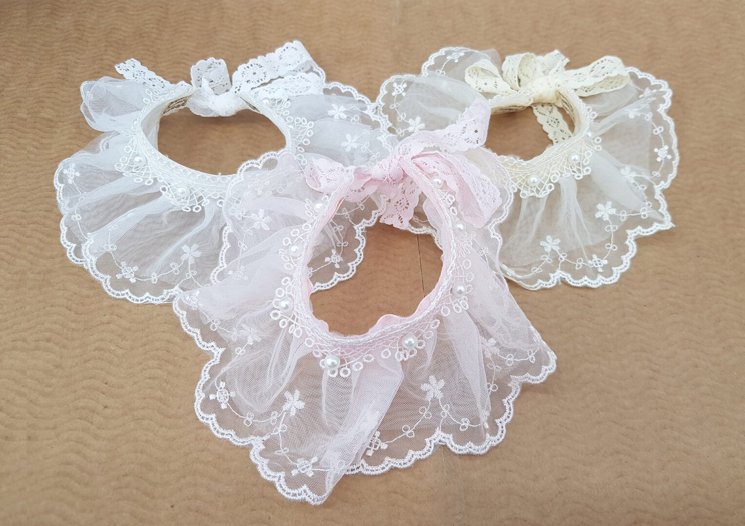 A group of three white and pink baby bibs.